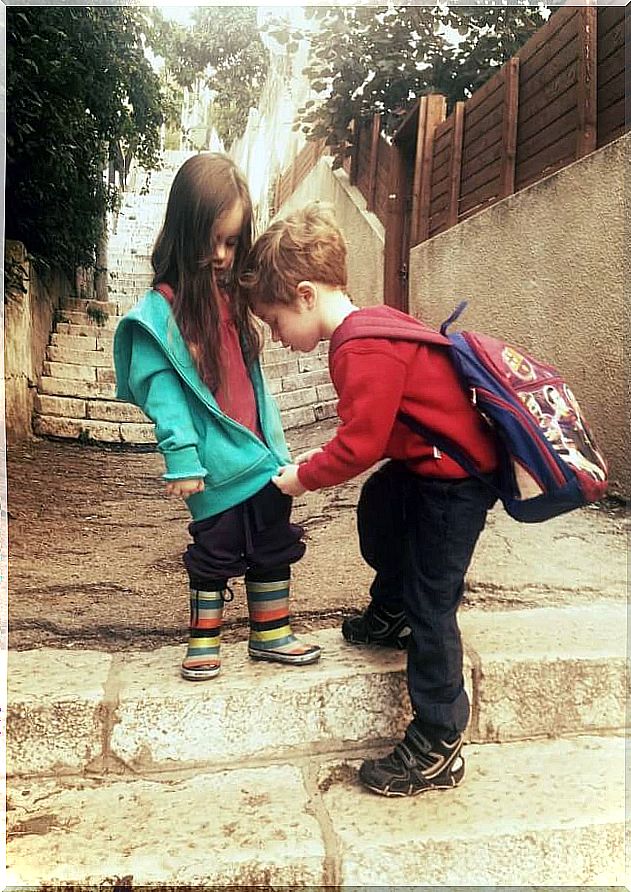 Brother helps his sister close the sweatshirt