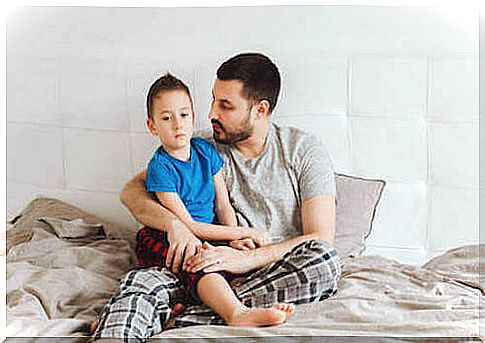 Father sitting on the bed holding his son.