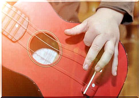 Child playing a red guitar.