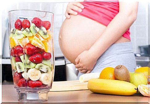 Mom with a big belly and fruit smoothies, an antidote for stomach acid in pregnancy.