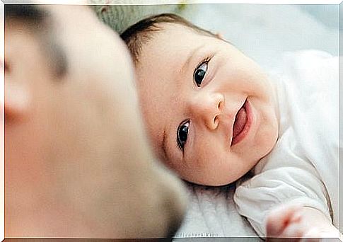 Infant smiling at father, example of John Bowlby's attachment theory