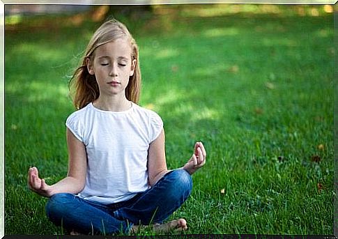 Little girl does meditation on a meadow