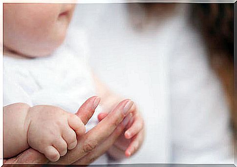 Newborn baby holding mother's finger.