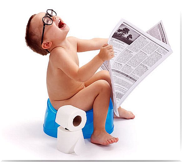 Child on the potty reads the newspaper.