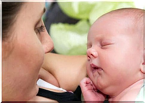 Newborn baby sleeping on mom's lap.