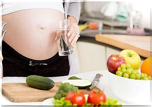 baby bump mom on table with fruits and vegetables